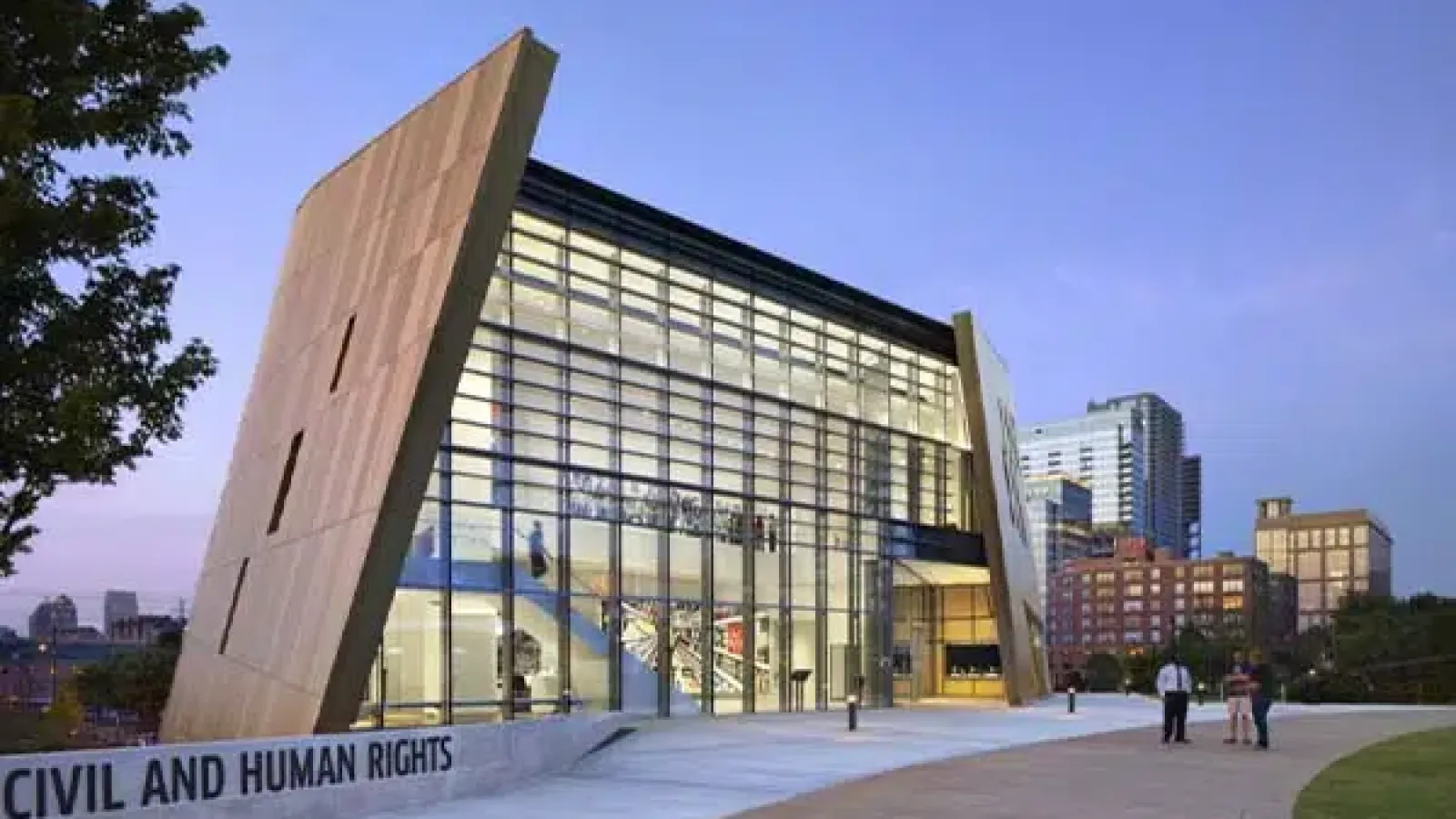 Modern Civil and Human Rights Museum with large glass facade at dusk in an urban setting with people nearby