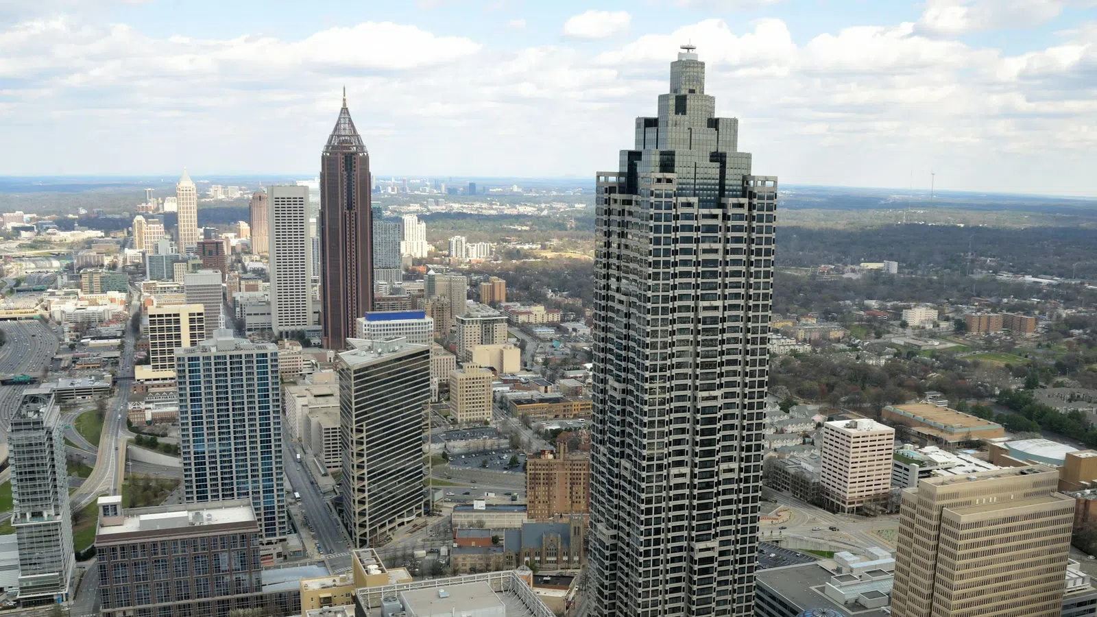 Aerial view of Atlanta skyline with skyscrapers under a partly cloudy sky during daytime.