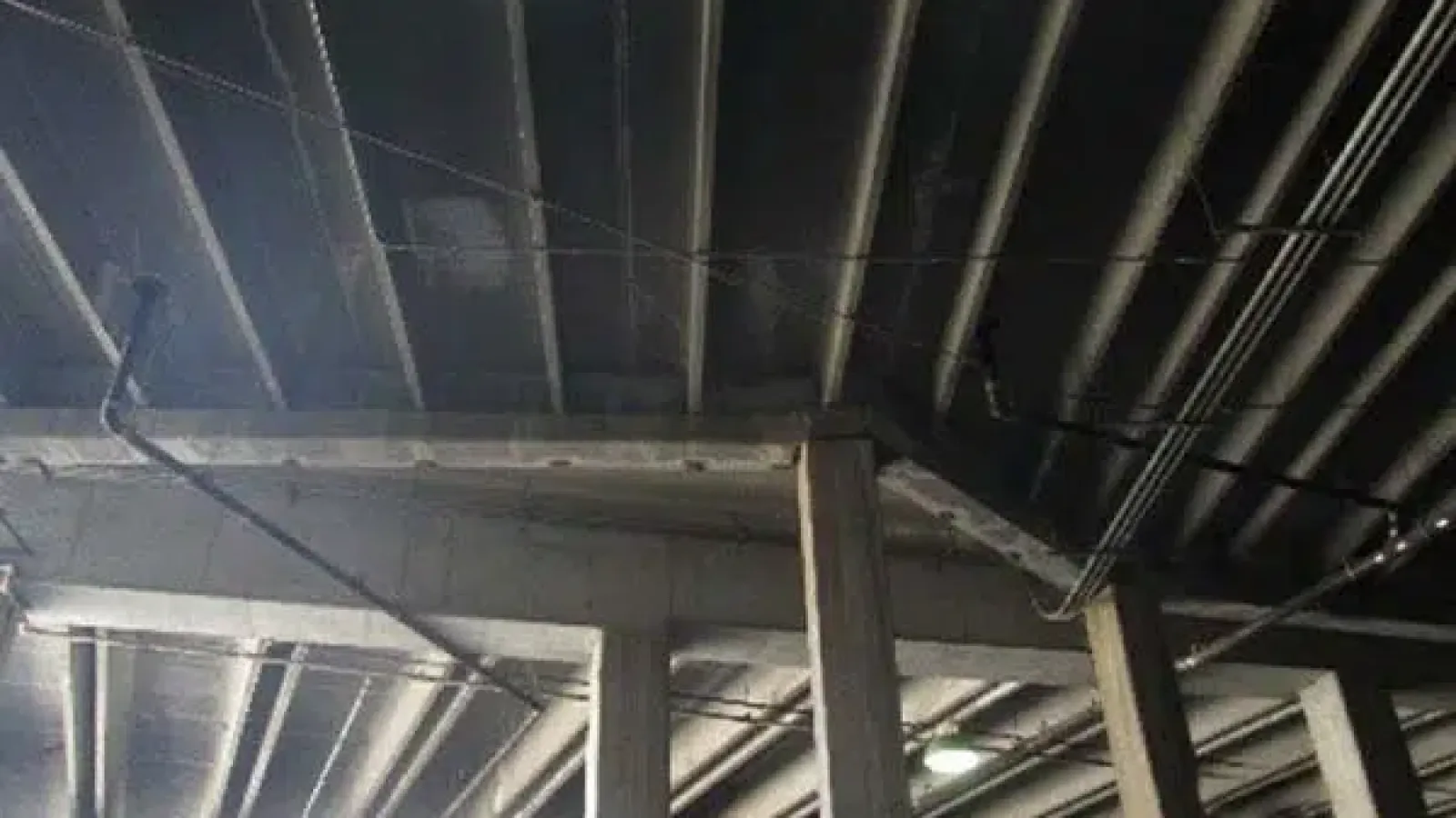 Interior view of a concrete ceiling with exposed beams and electrical conduits in an industrial building