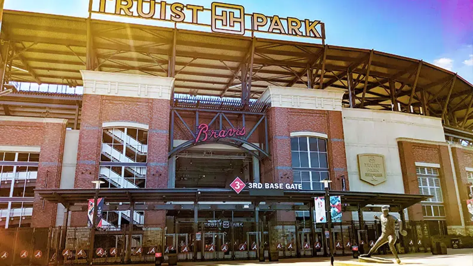 Exterior view of Truist Park baseball stadium with 3rd Base Gate and Braves signage under clear sky.