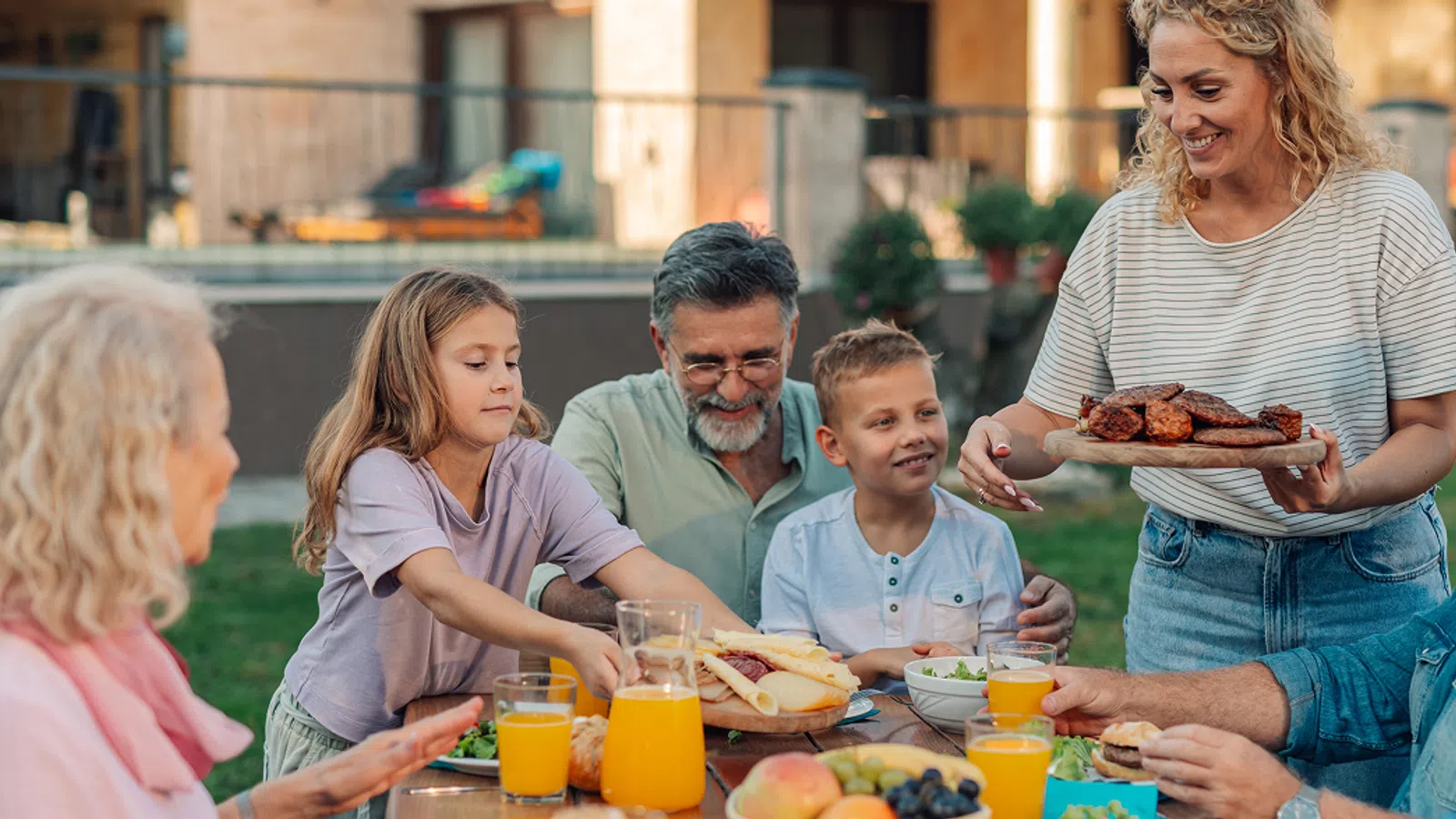 Multigenerational family enjoying a backyard meal with fresh food and drinks on a sunny day