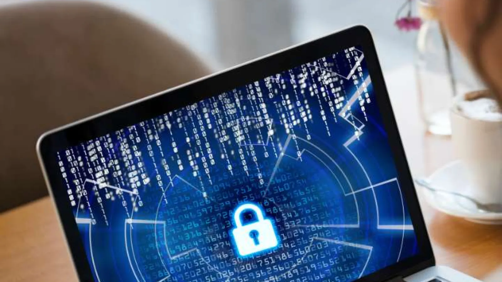 Person using laptop with digital lock and data security graphics on screen representing cybersecurity.