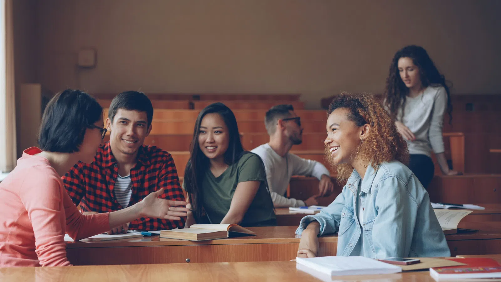 Group of diverse college students studying and discussing together in a university lecture hall.