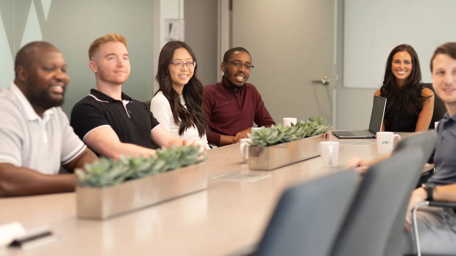 Diverse group of professionals seated around conference table in modern office during meeting.