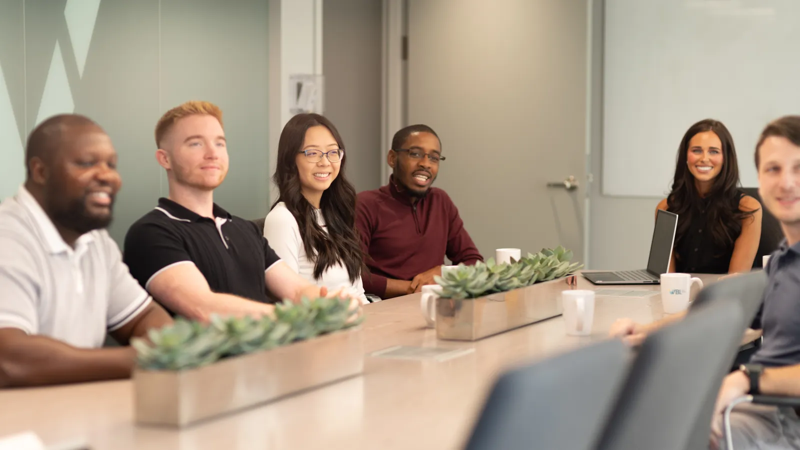 Diverse group of professionals seated around conference table in modern office during meeting.