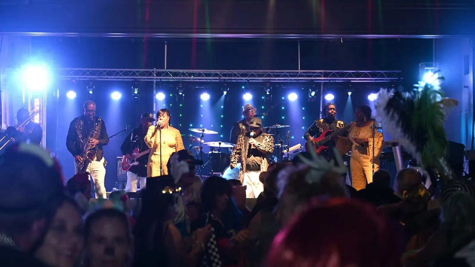 Live band performing on stage with vibrant blue lights and crowd enjoying the music at night event