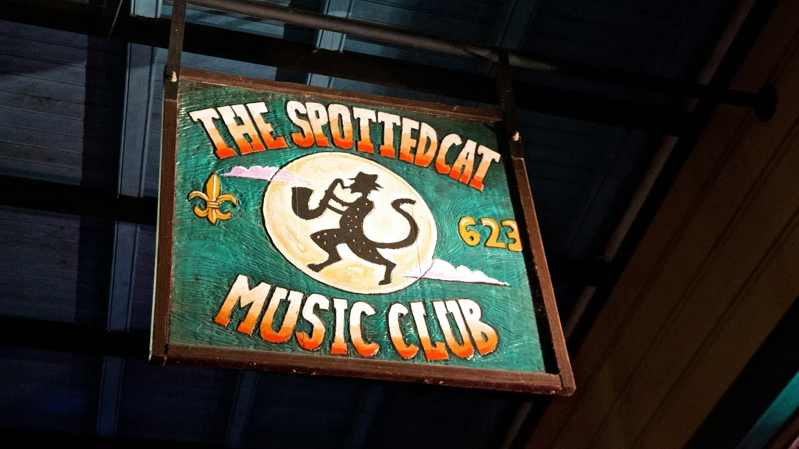 Wooden sign for The Spotted Cat Music Club with a silhouetted cat musician playing saxophone.