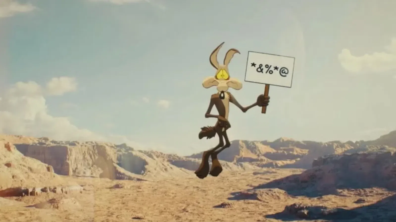 Cartoon coyote holds a sign with symbols in a desert canyon landscape under a clear sky.