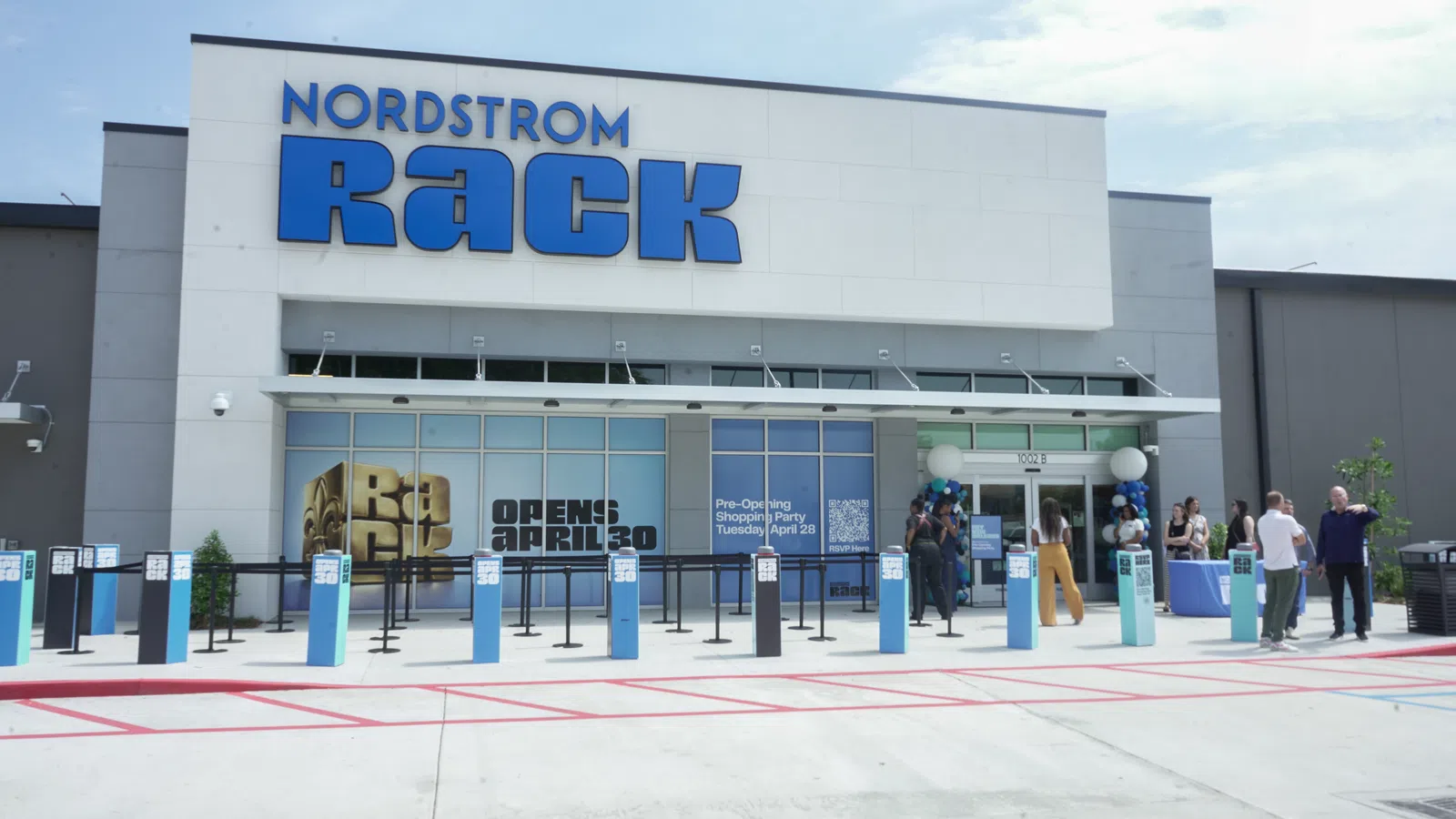 Nordstrom Rack store front with blue signage and people gathered outside for pre-opening event.