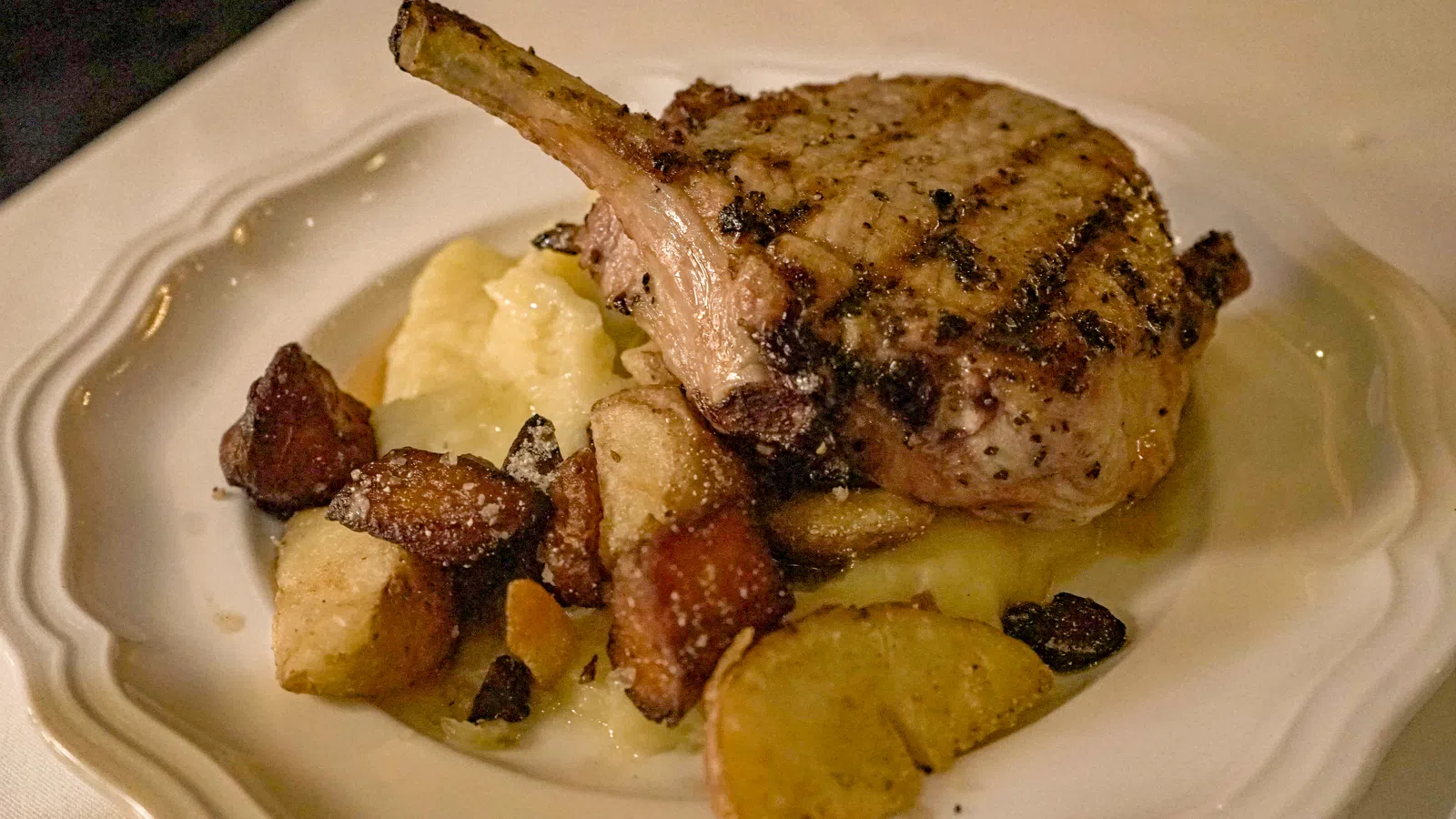 Grilled pork chop served with mashed potatoes and roasted vegetables on a white plate