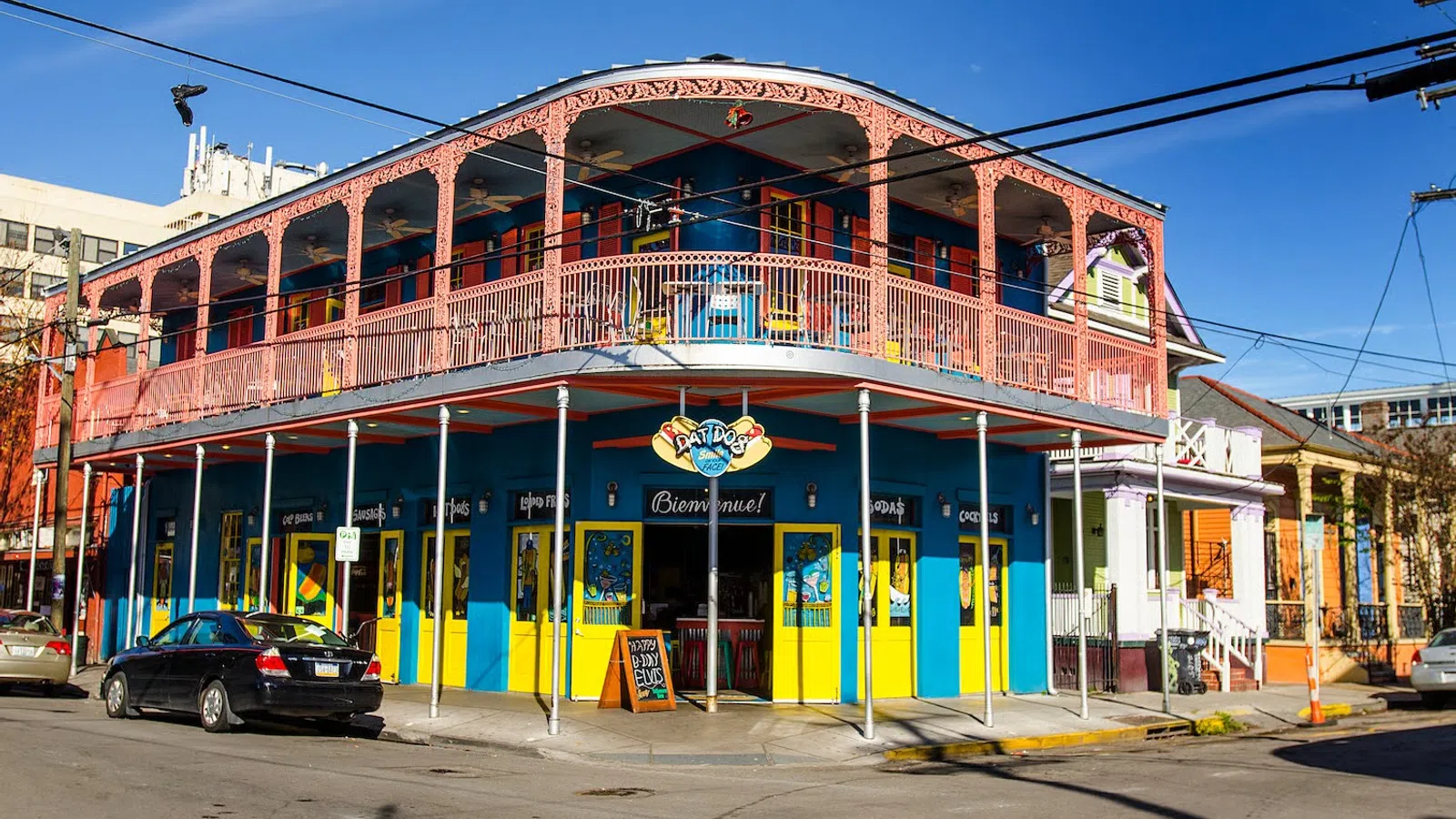 Colorful two-story building with yellow and blue walls and pink balcony railing at street corner in sunny weather