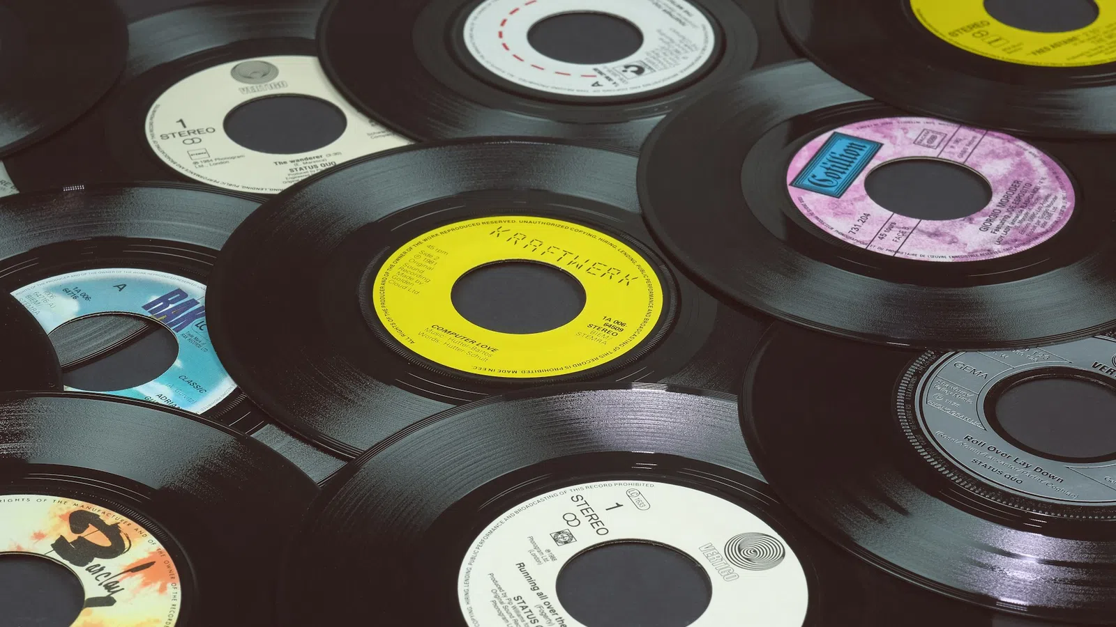 A collection of vintage 45 RPM vinyl records with colorful center labels overlapping on a flat surface.