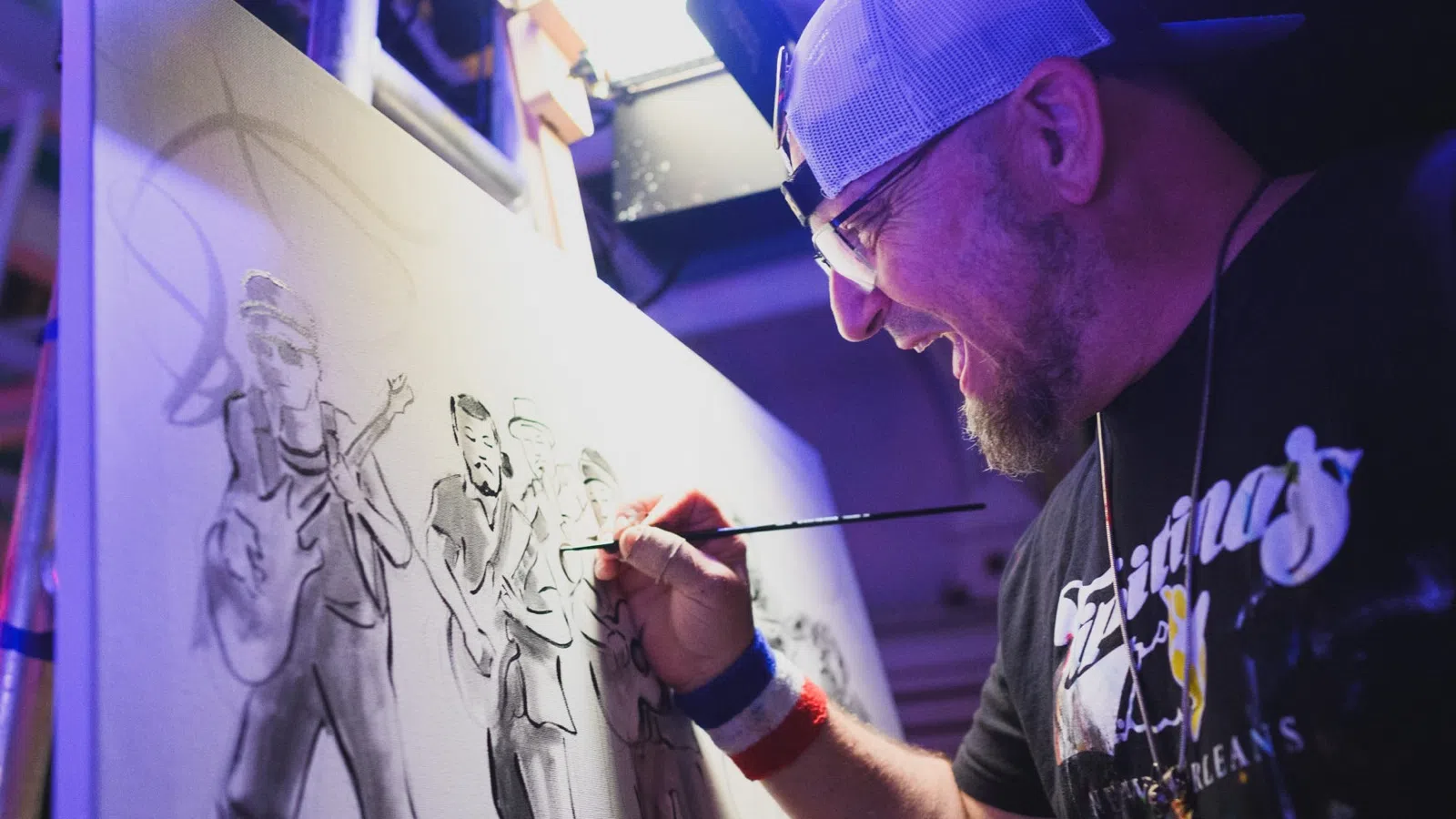 Artist in cap painting a monochrome group portrait on canvas in a studio with focused expression