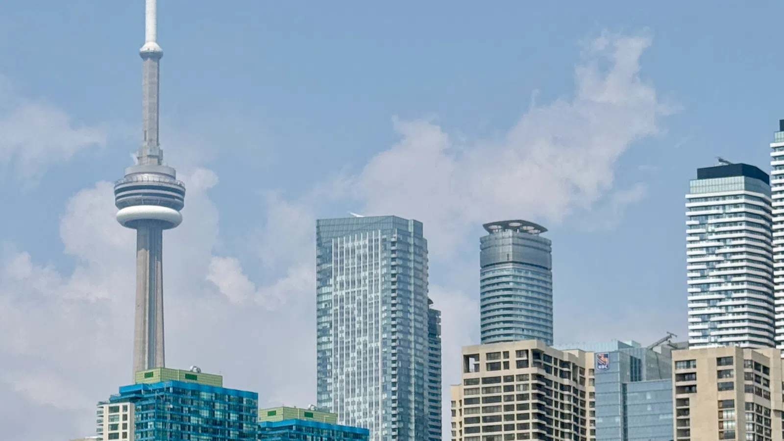Toronto skyline with CN Tower and modern skyscrapers under a partly cloudy sky on a clear day