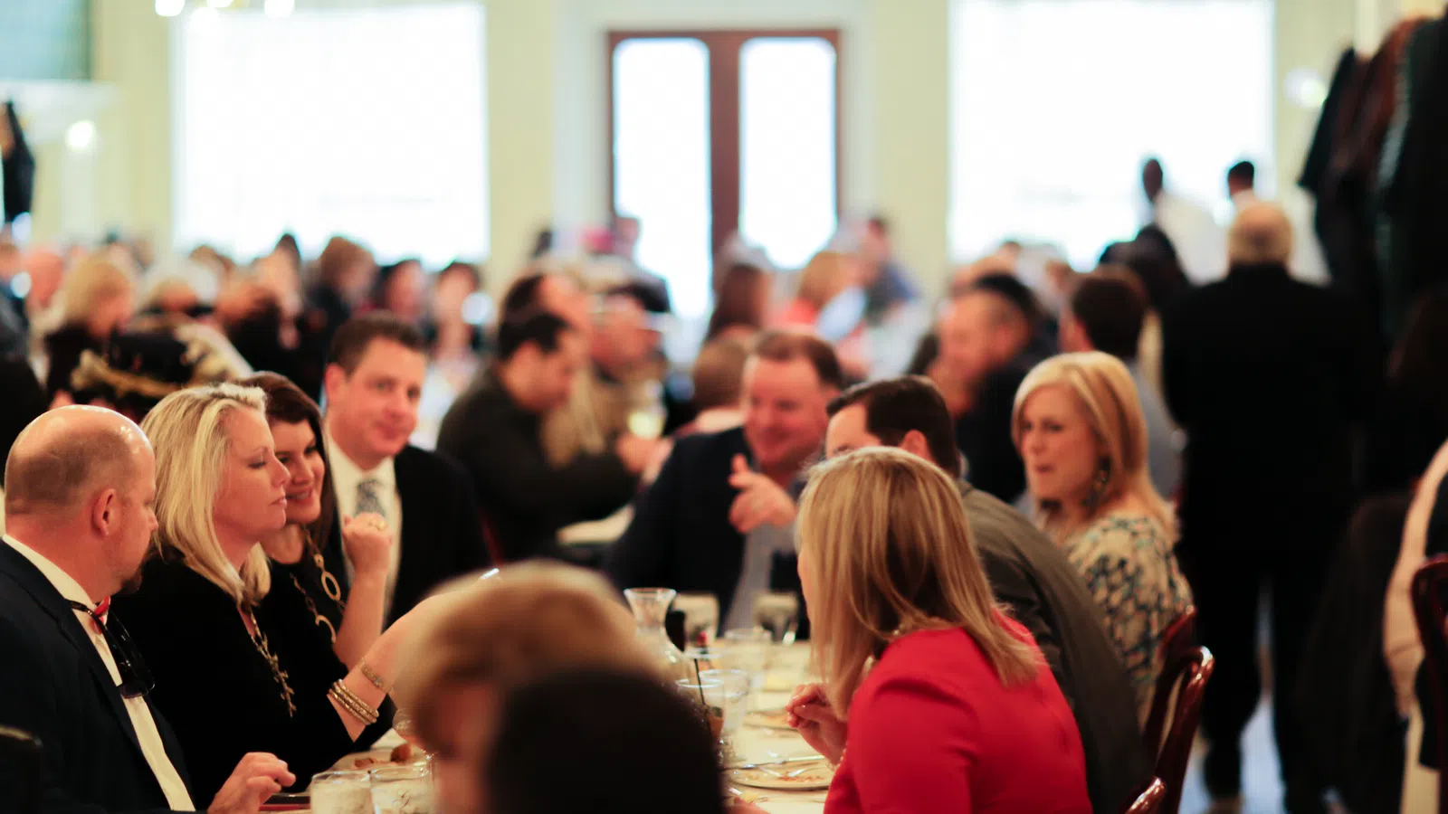 People enjoying a social gathering at a restaurant with conversations and dining in a warm, well-lit atmosphere.