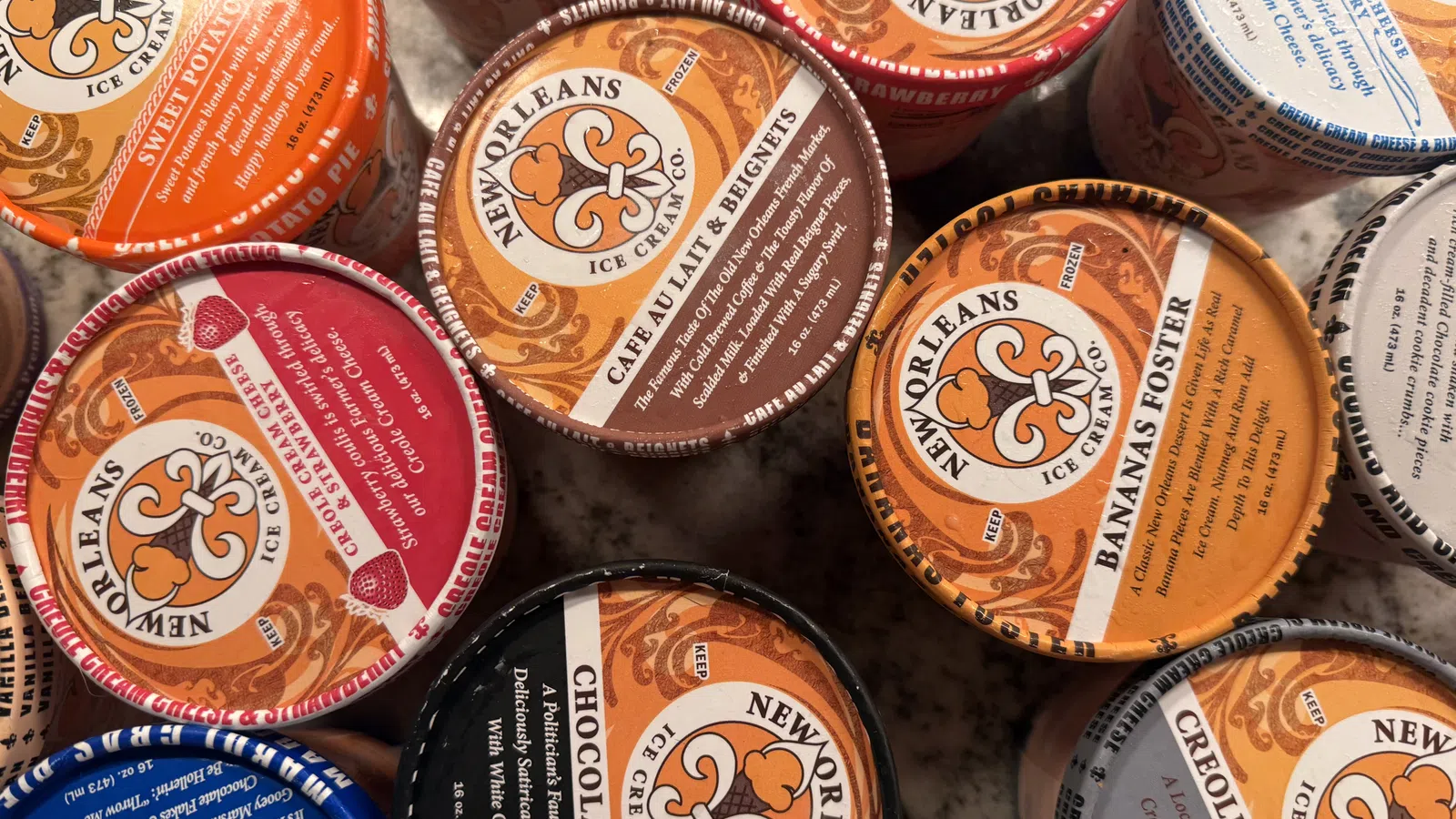 Top view of assorted New Orleans Ice Cream Company pints with various colorful flavors labeled on lids.