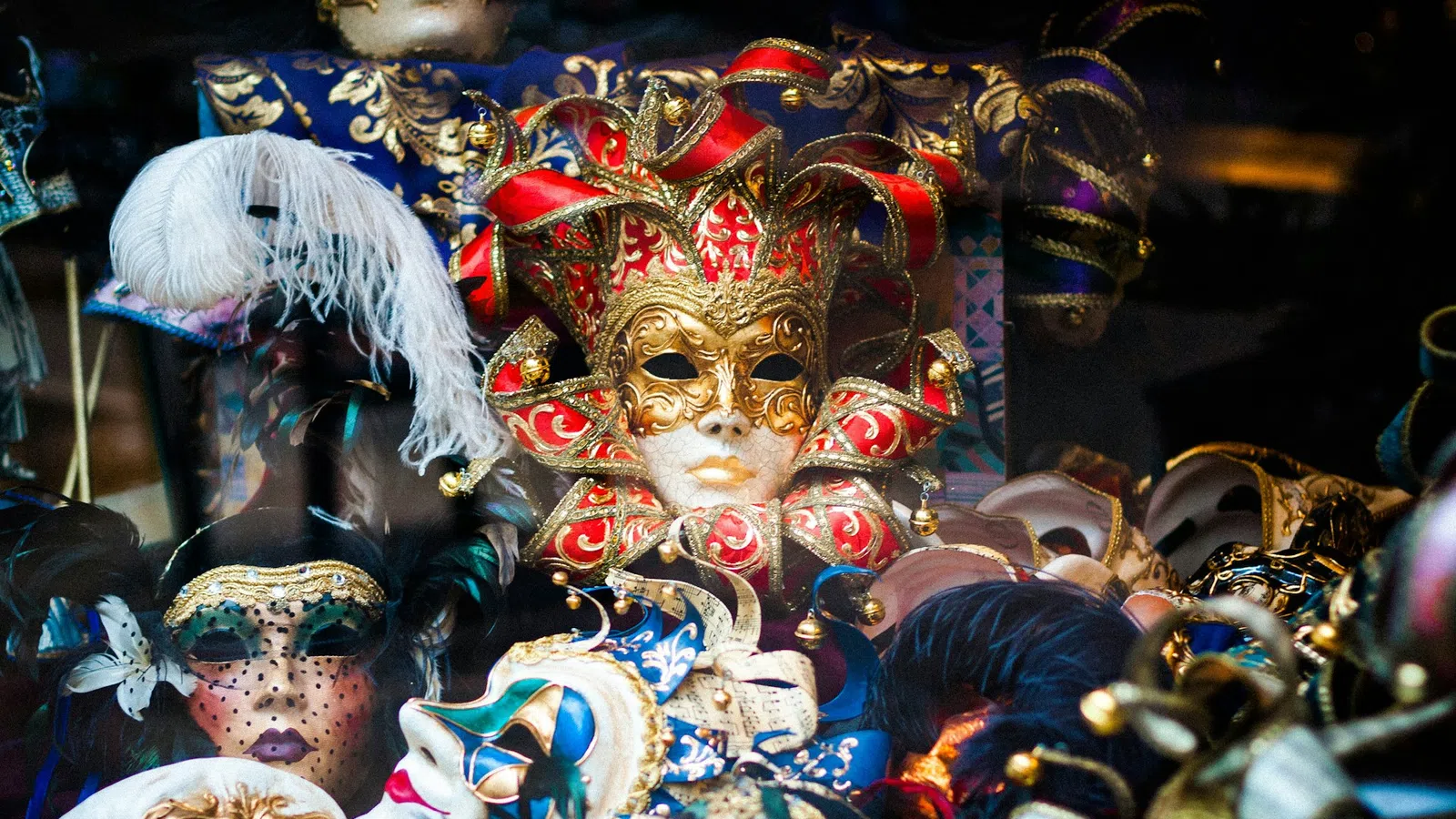 Colorful Venetian carnival masks with intricate designs, feathers, and gold accents on display