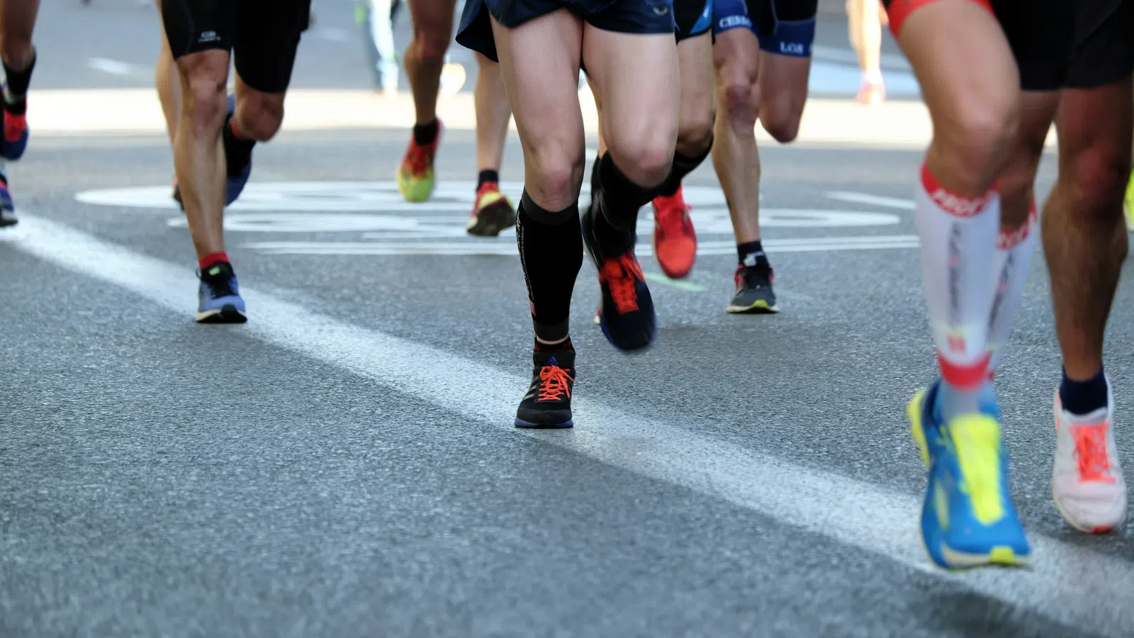Close-up of runners' legs and feet in athletic shoes on a city road during a race event