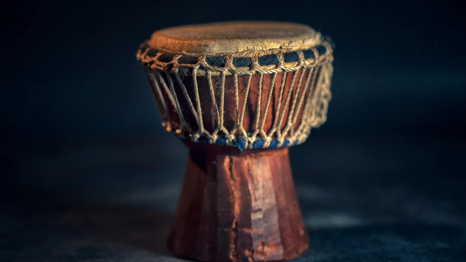 Close-up of a traditional wooden drum with rope tensioning on a dark background