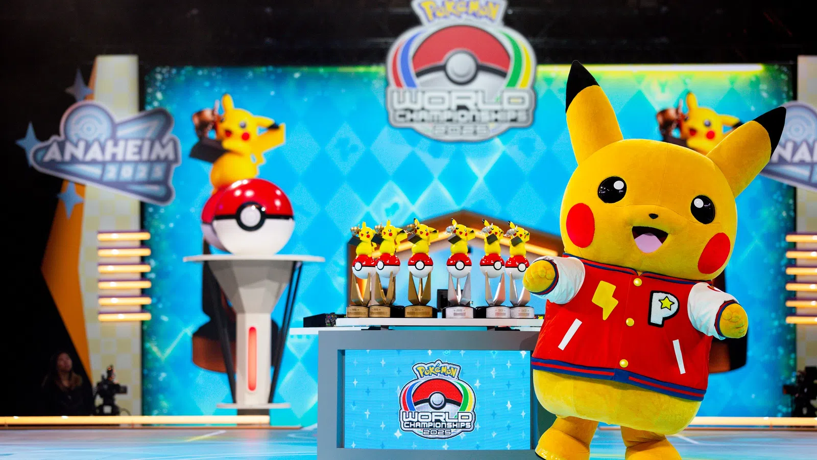 Pikachu mascot in red jacket poses near trophies at Pokémon World Championships in Anaheim 2022 event.