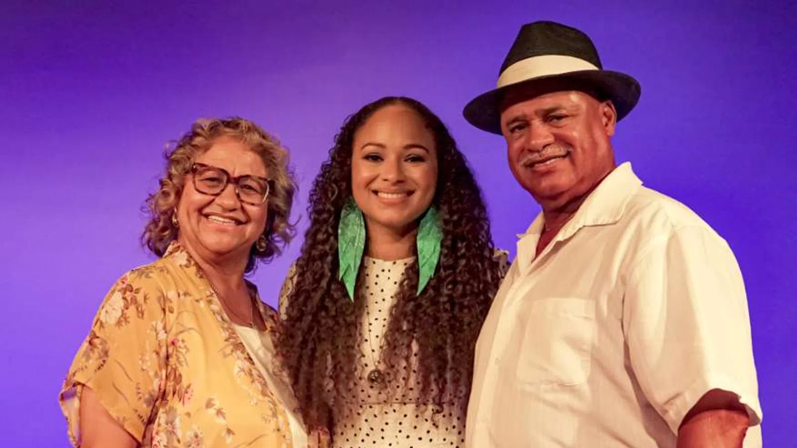 Smiling three generations family portrait with purple background and casual summer clothing