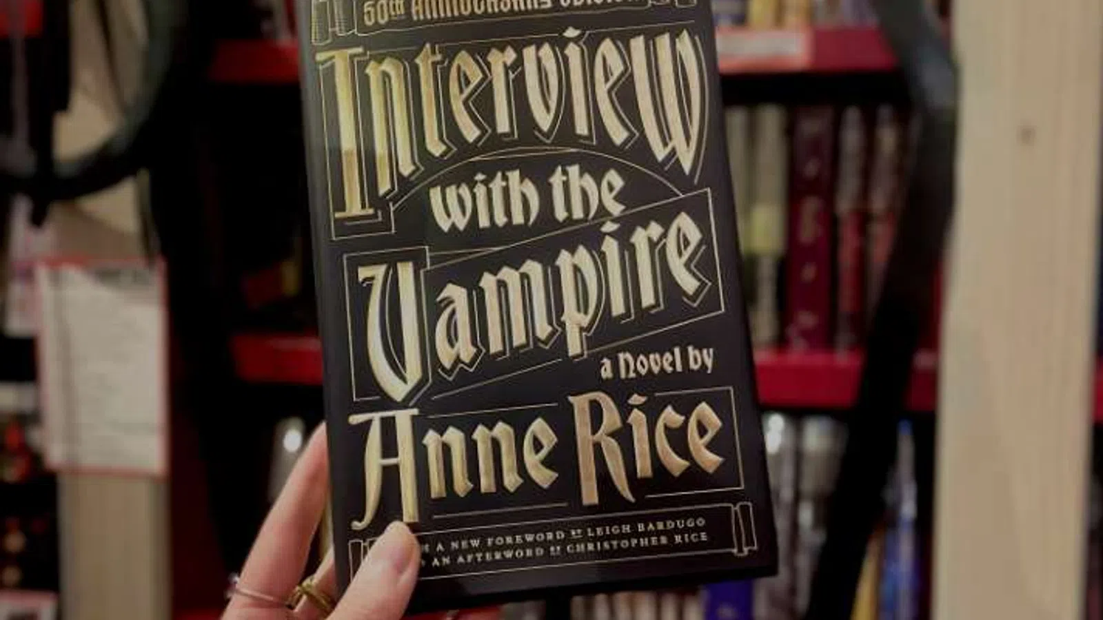 Hand holding the 50th Anniversary Edition of Interview with the Vampire by Anne Rice with overlaid text on the book cover.
