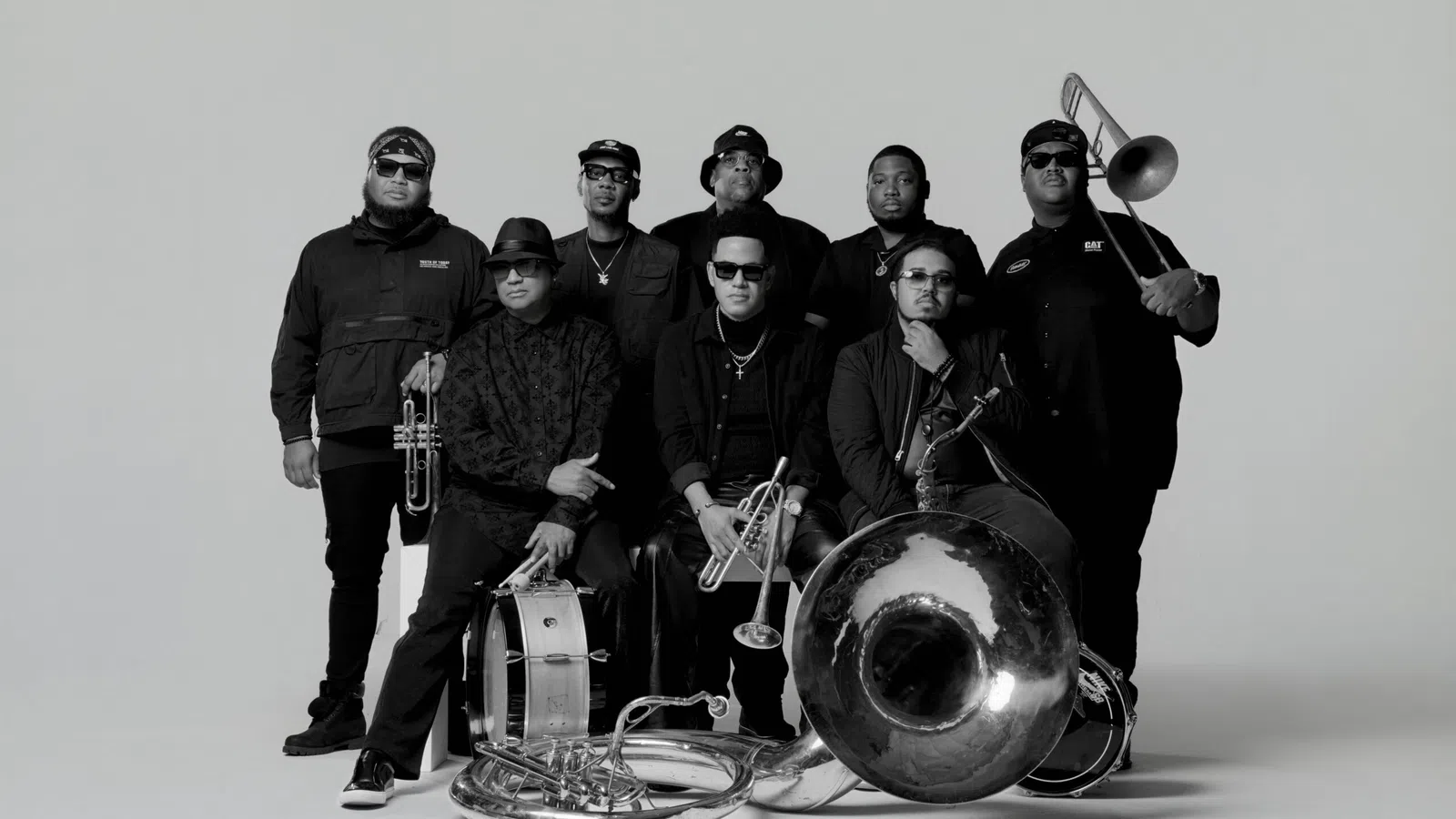 Black and white photo of an eight-member brass band with instruments including trumpet, trombone, and drums.