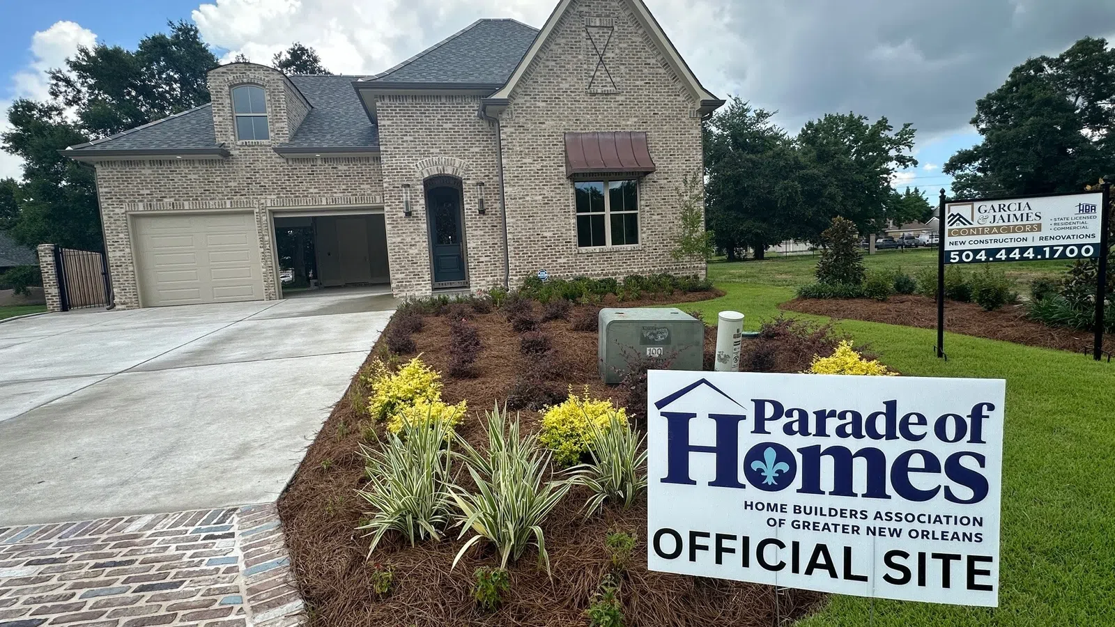 New brick home with landscaping and Parade of Homes official site sign in front yard under cloudy sky.