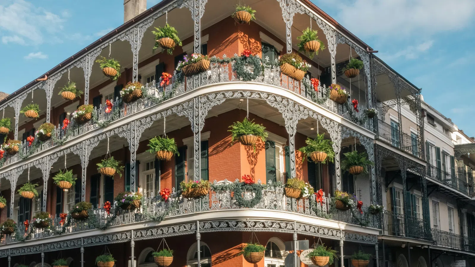 Historic building with ornate iron balconies adorned with hanging flower pots in French Quarter, New Orleans.