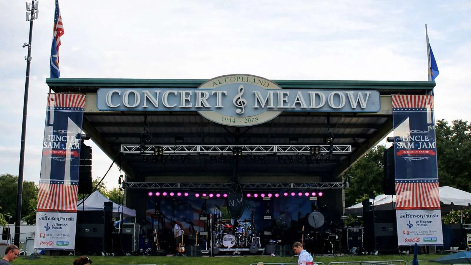 Outdoor stage setup at Al Copeland Concert & Meadow with banners for Uncle Sam Jam event and audience seating.