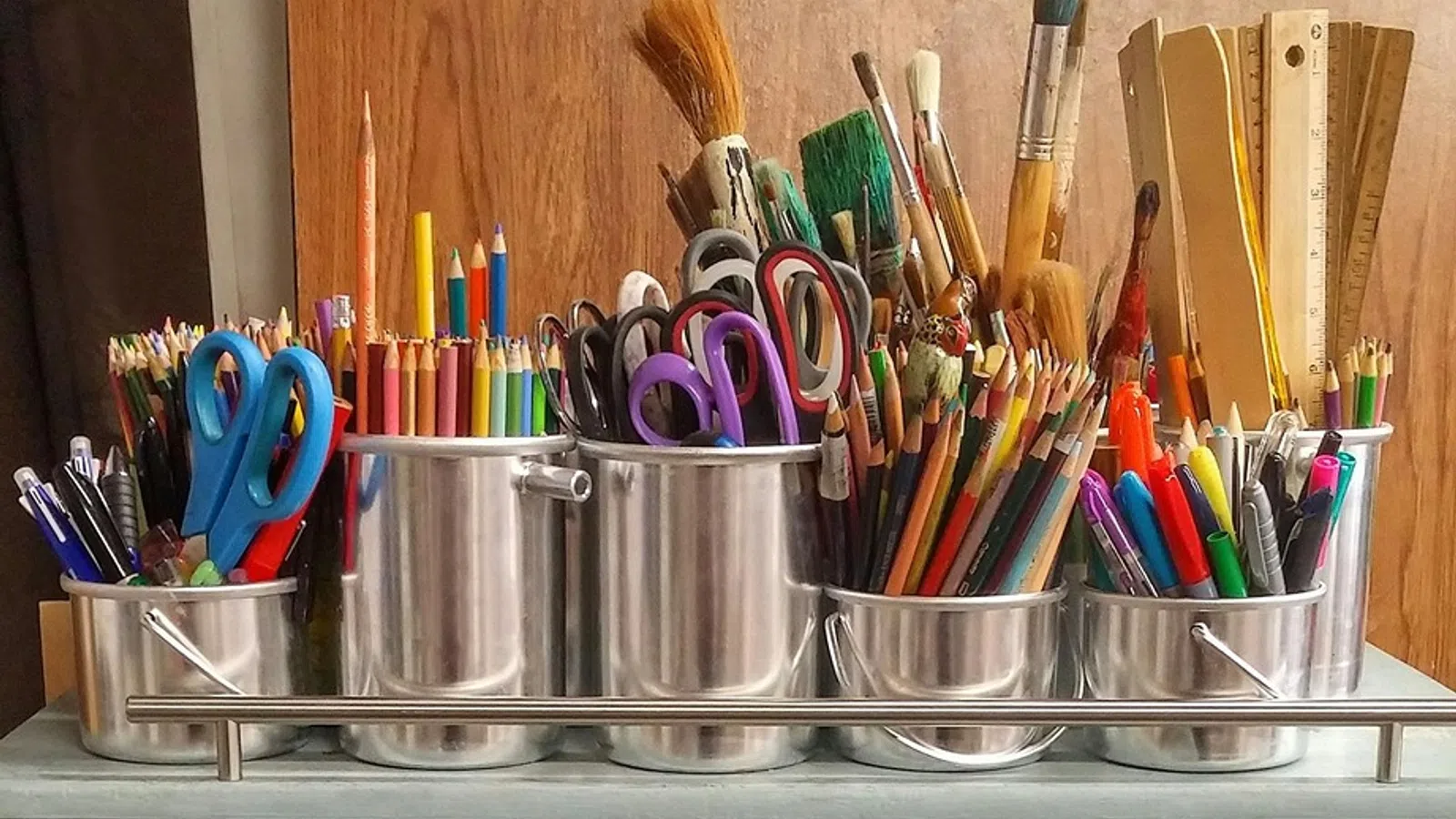 a group of pens and pencils in a glass holder