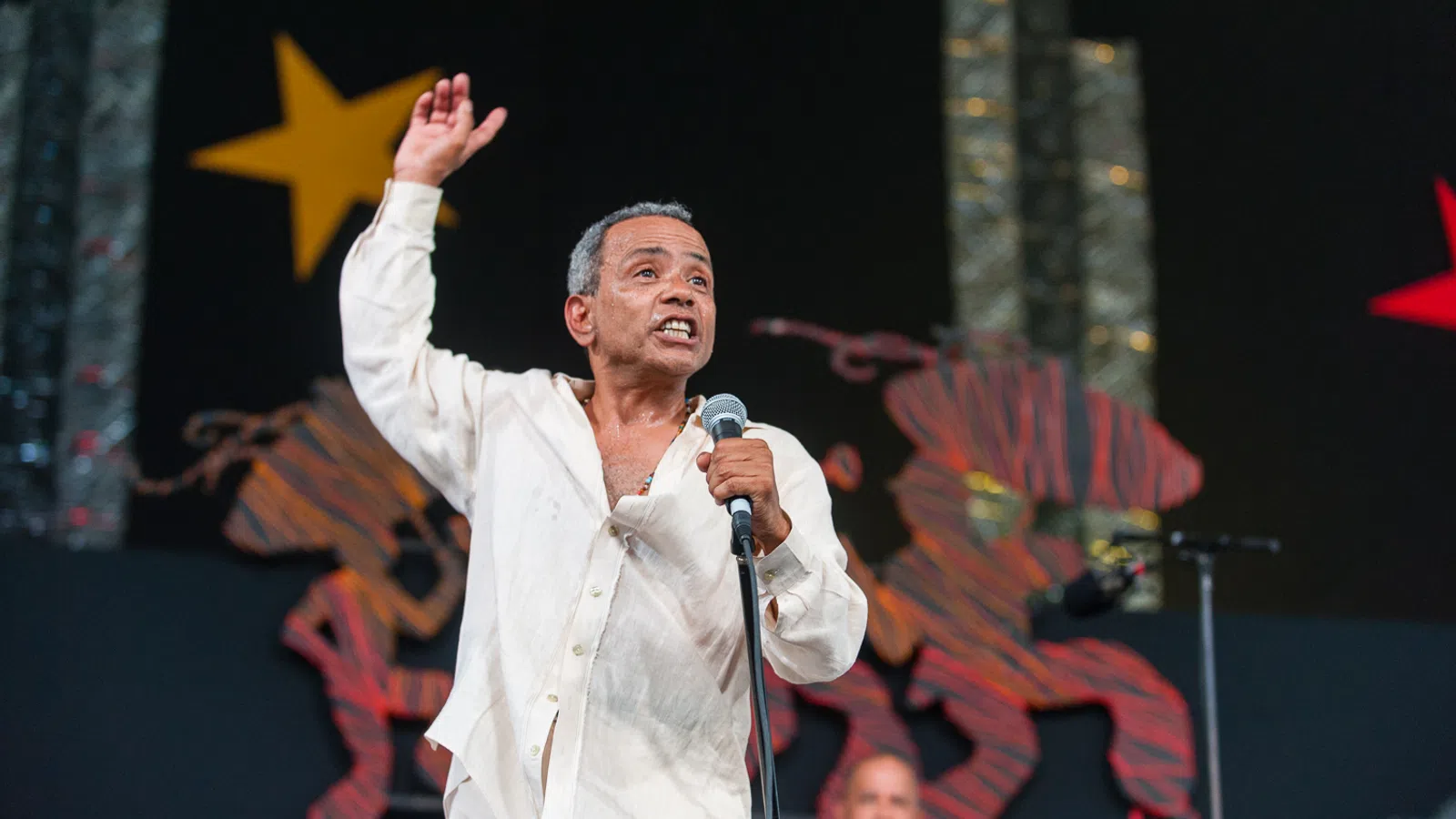 John Boutté holding a microphone and standing on a stage