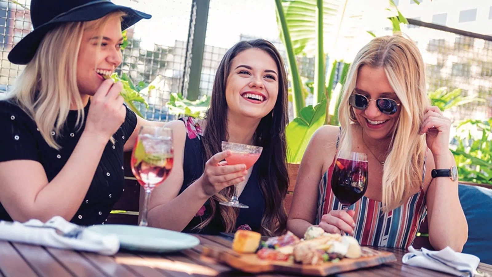 a group of women sitting at a table with food and drinks