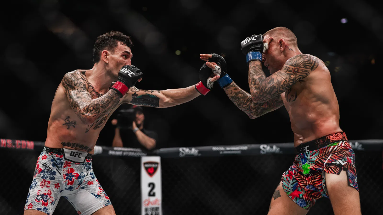 Two tattooed UFC fighters exchange punches inside the Octagon during a mixed martial arts match.