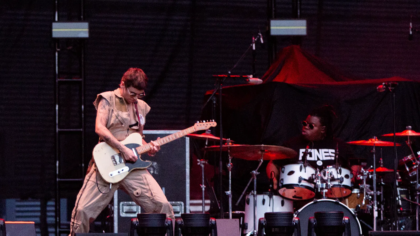 a man playing a guitar on a stage with a man playing drums