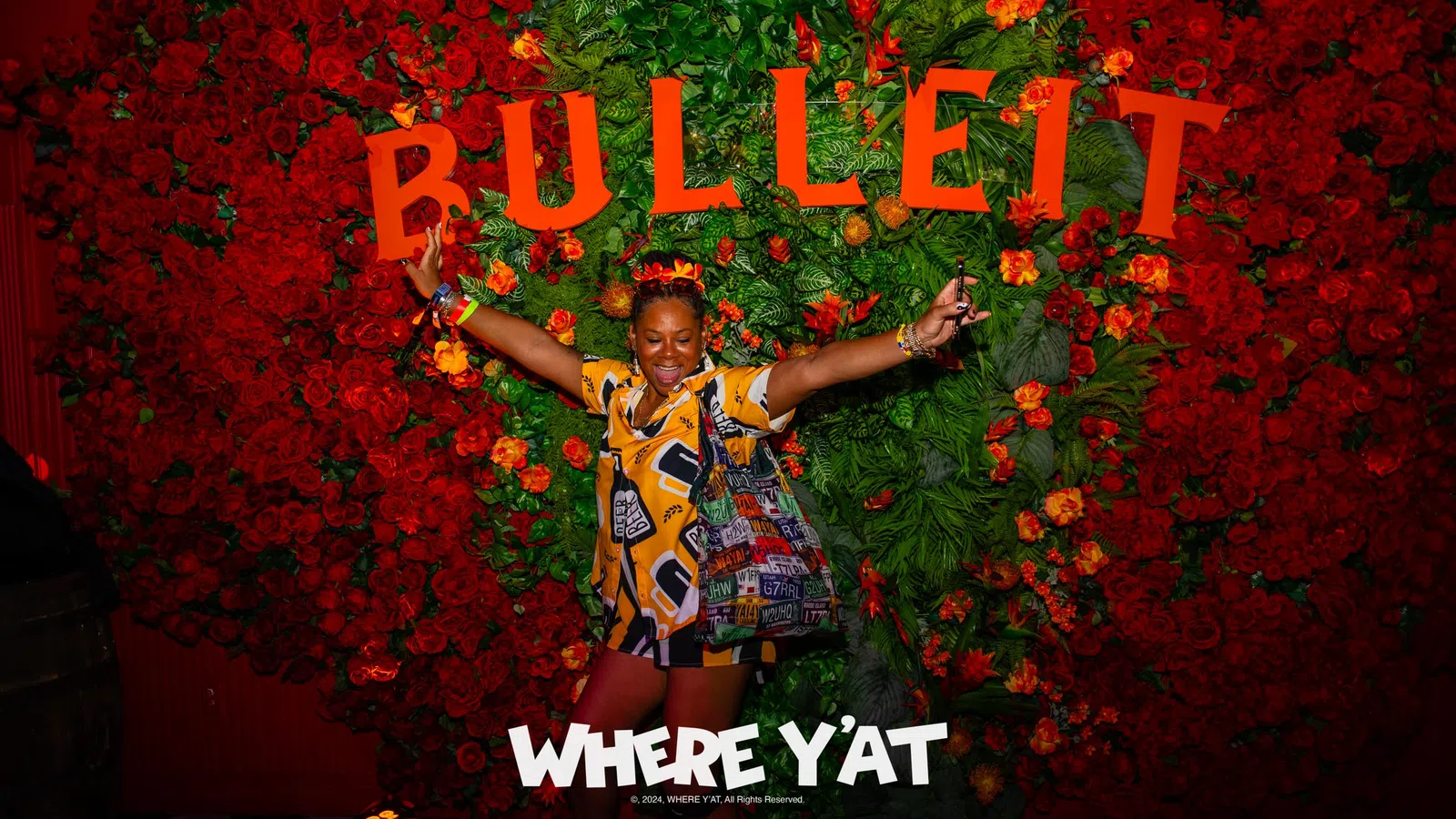 a person posing in front of a wall of flowers