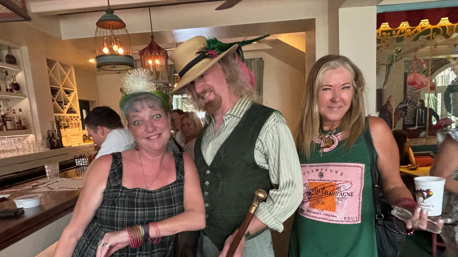 Three smiling individuals in festive attire enjoying time at a lively social gathering.