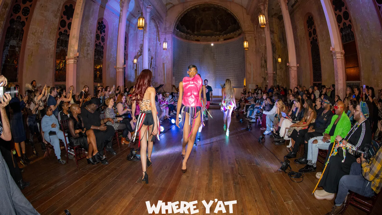 a group of women walking down a hall with people sitting on the floor
