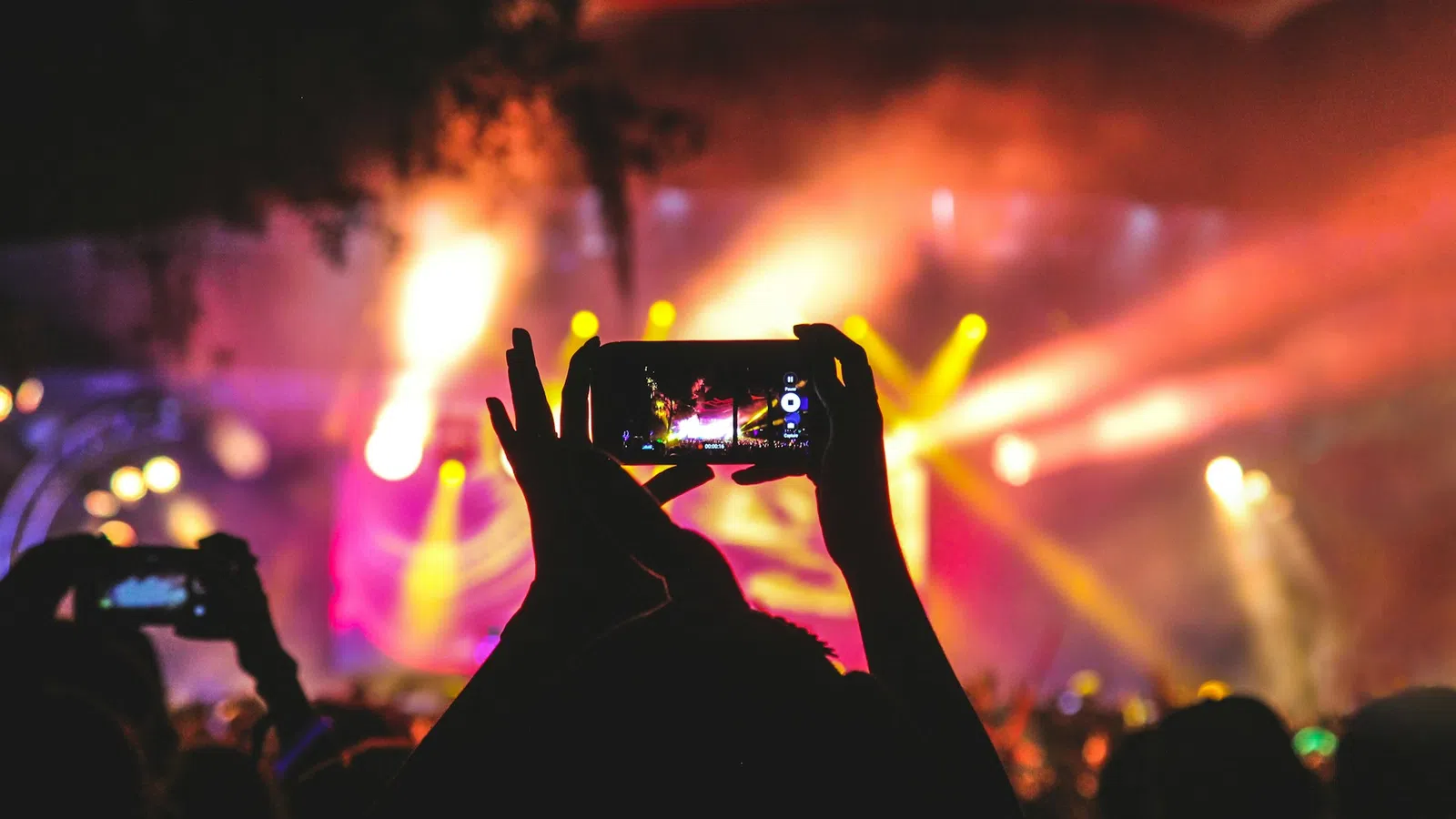 a person holding a camera in front of a crowd