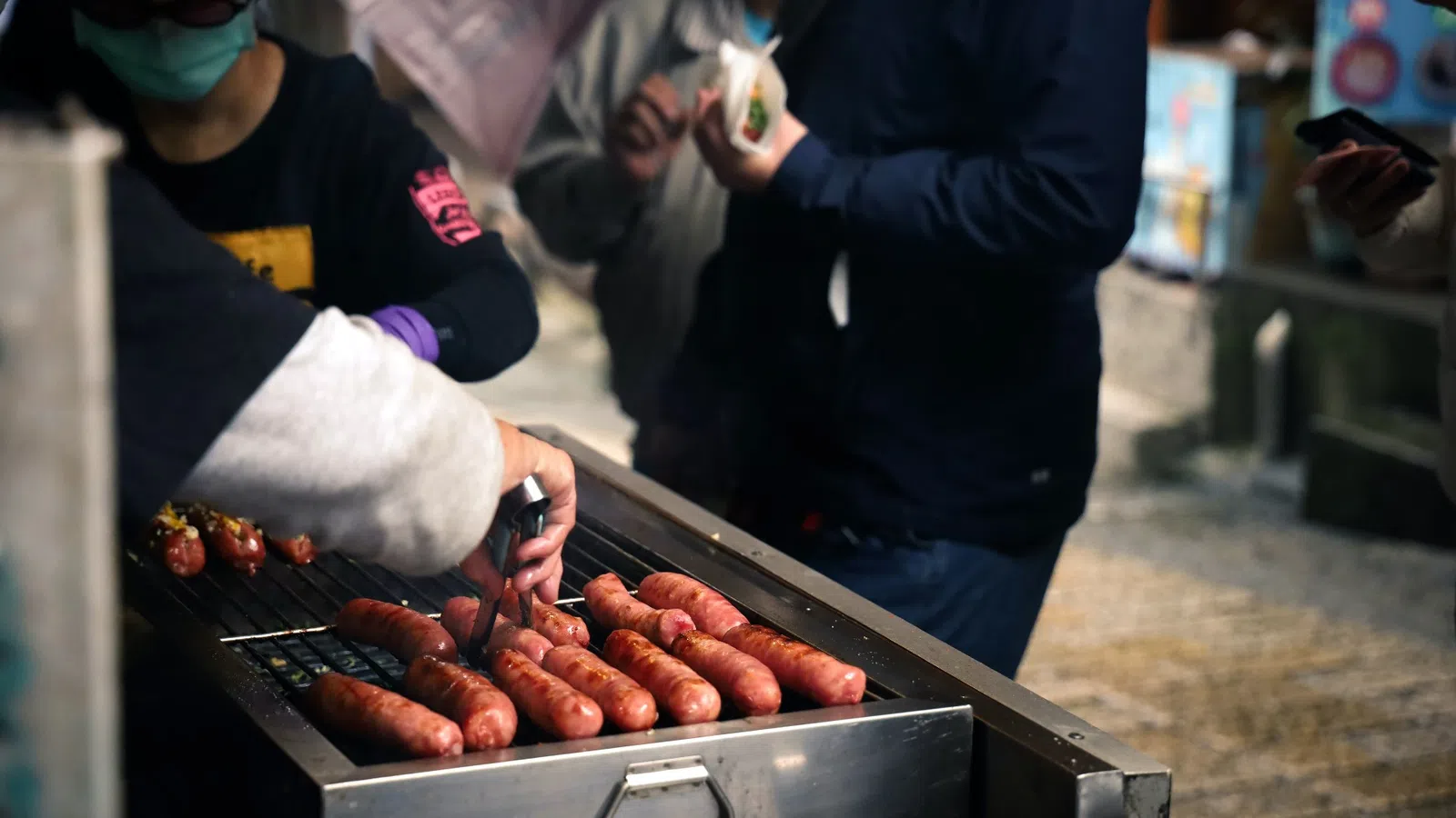 a person cooking hot dogs on a grill