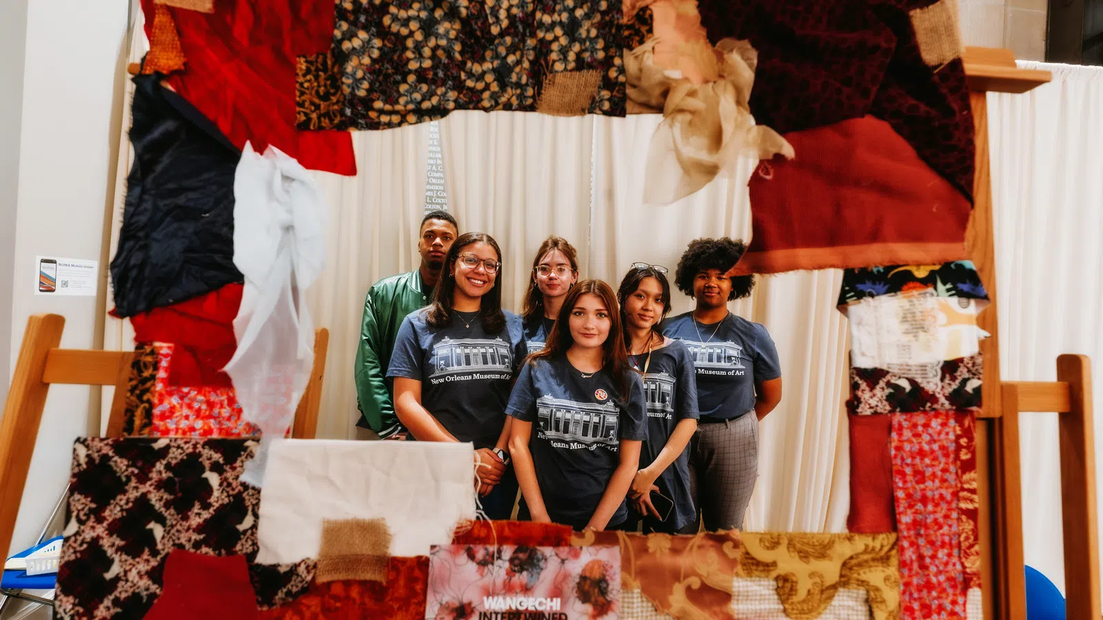 a group of people posing for a photo in front of a bed