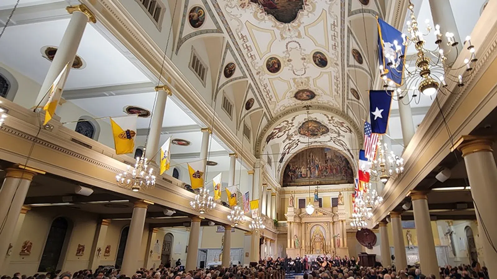 a large group of people in a church with St. Louis Cathedral in the background