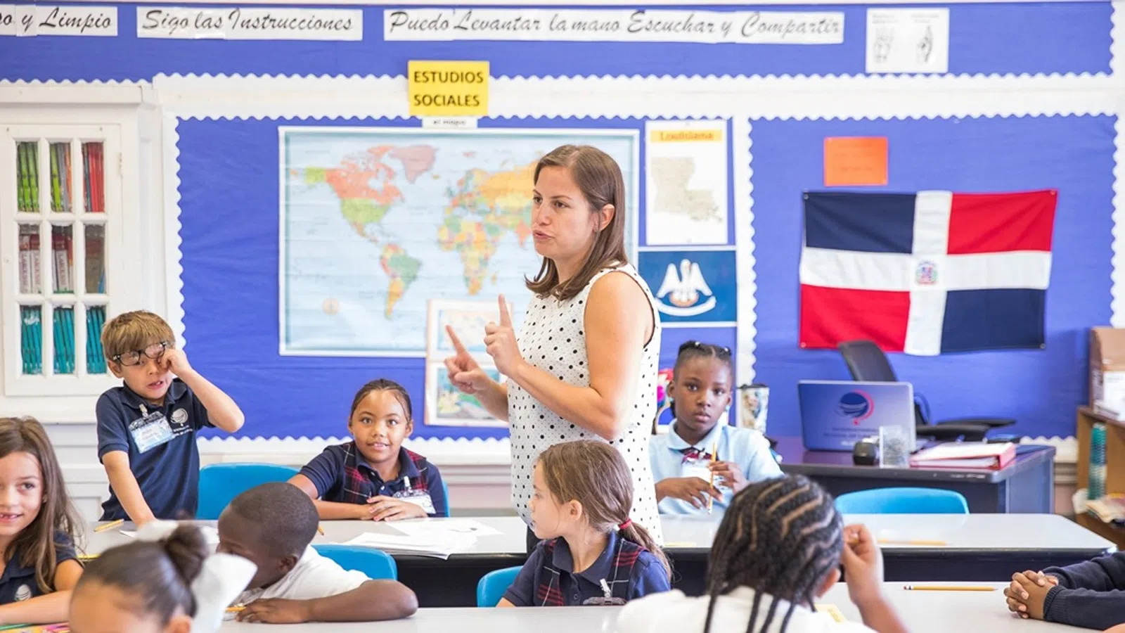 a person standing in front of a group of children sitting in a classroom