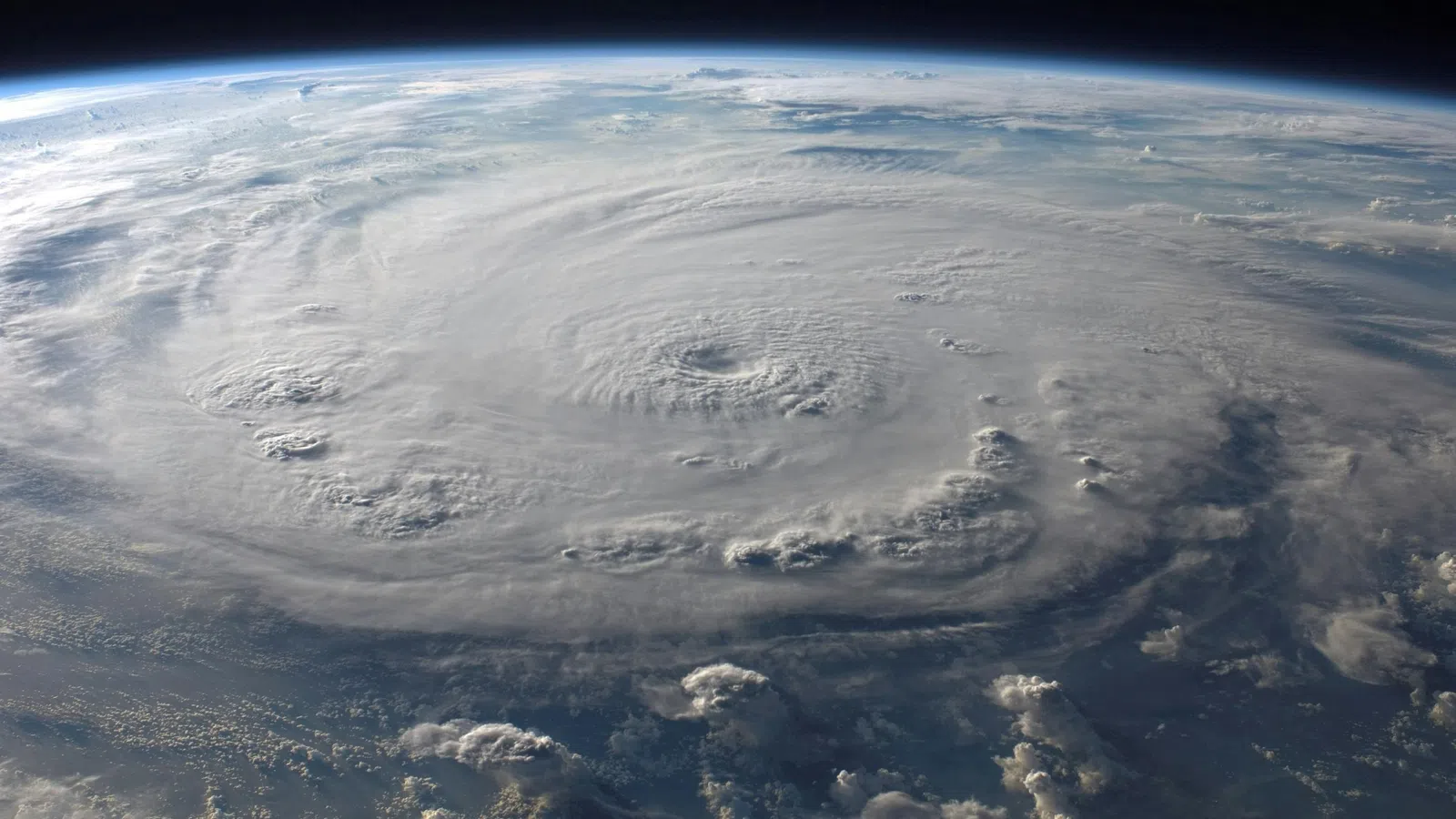 Satellite view of a massive hurricane swirling over the Earth's ocean surface under the atmosphere.