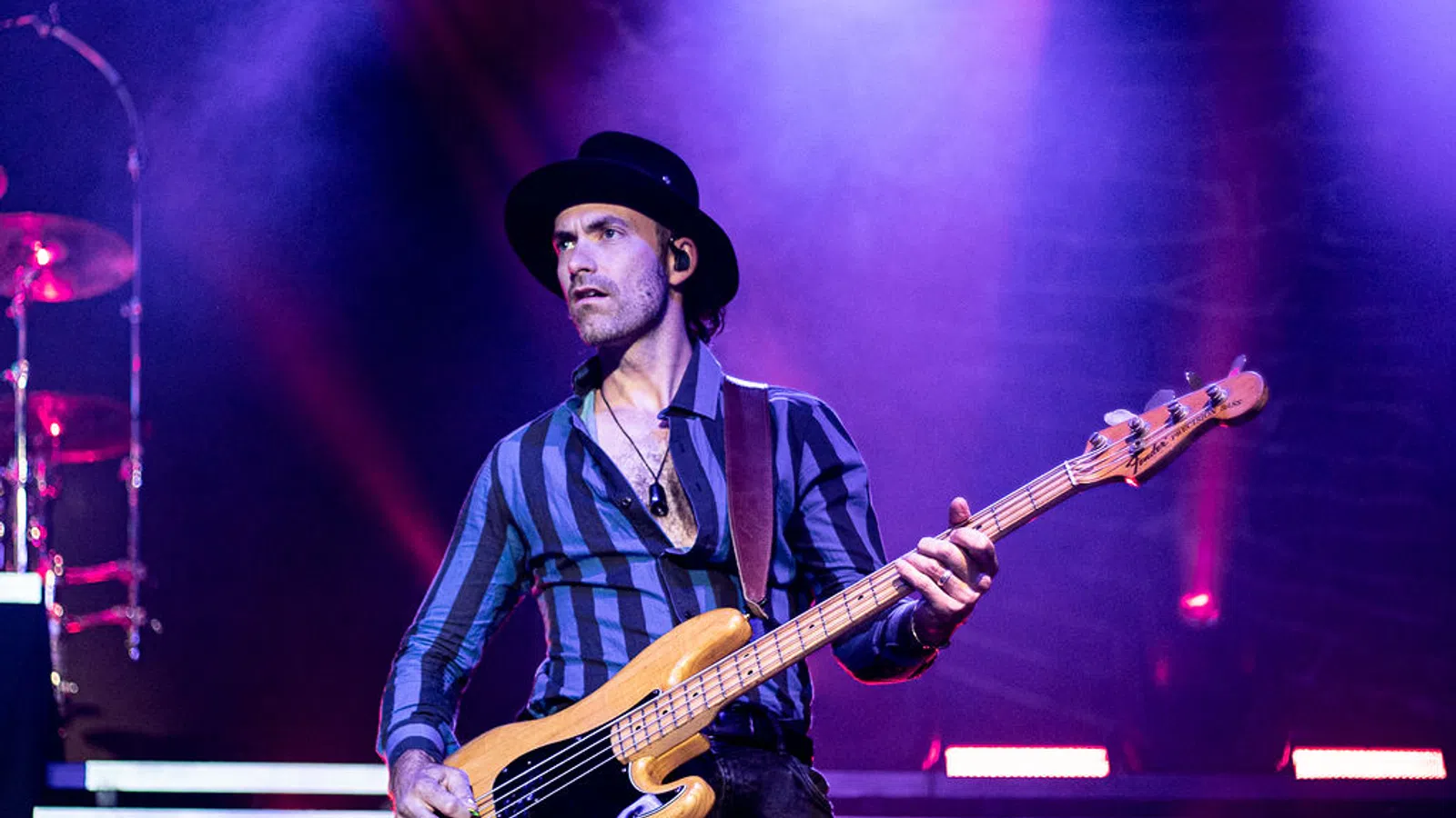 a man playing a guitar on a stage with Old National Centre in the background