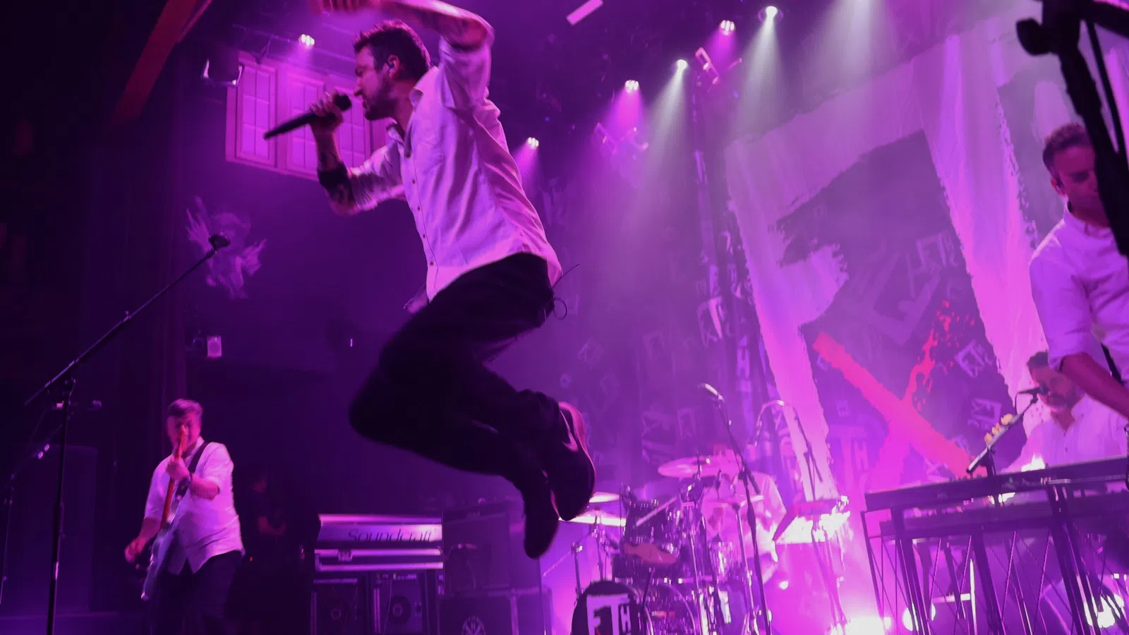 a man jumping in the air with a microphone and a drum set