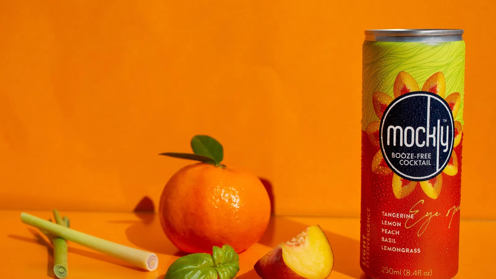 a can of soda next to a fruit and a glass of orange juice