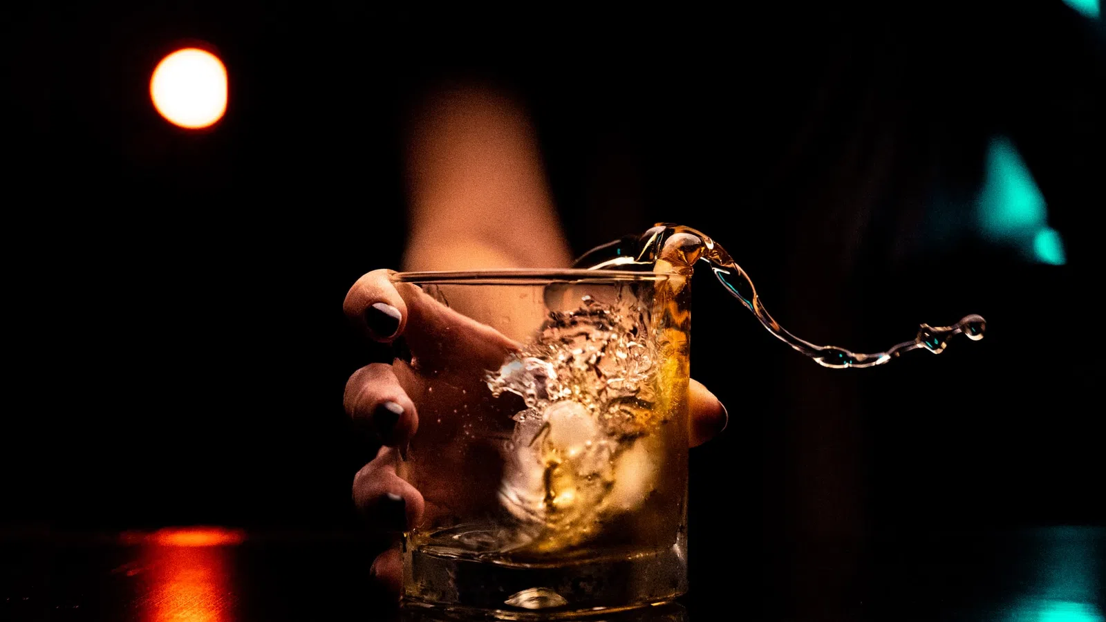 a hand pouring a drink into a glass