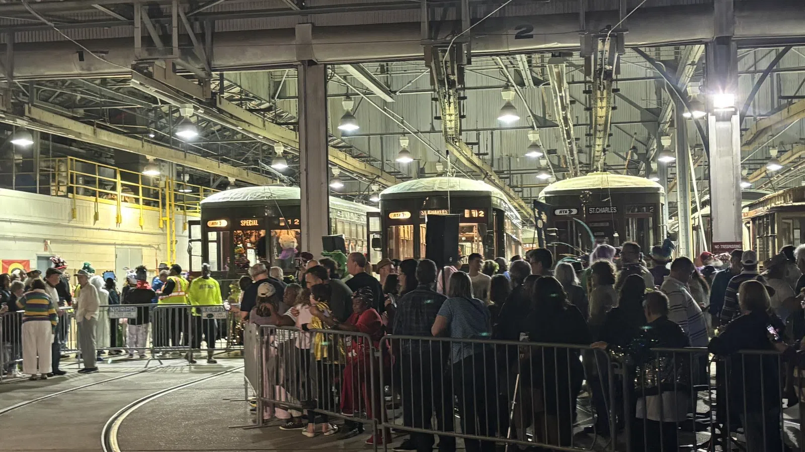 Crowd of people inside a large train depot with vintage streetcars and industrial lighting overhead