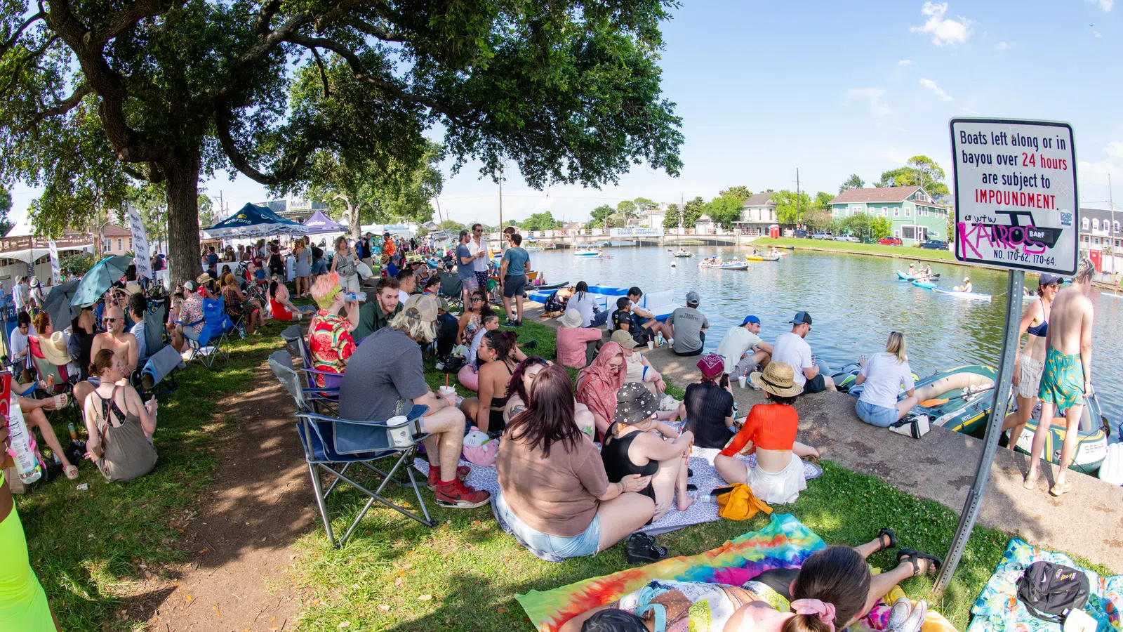 a group of people sitting on the grass by a body of water